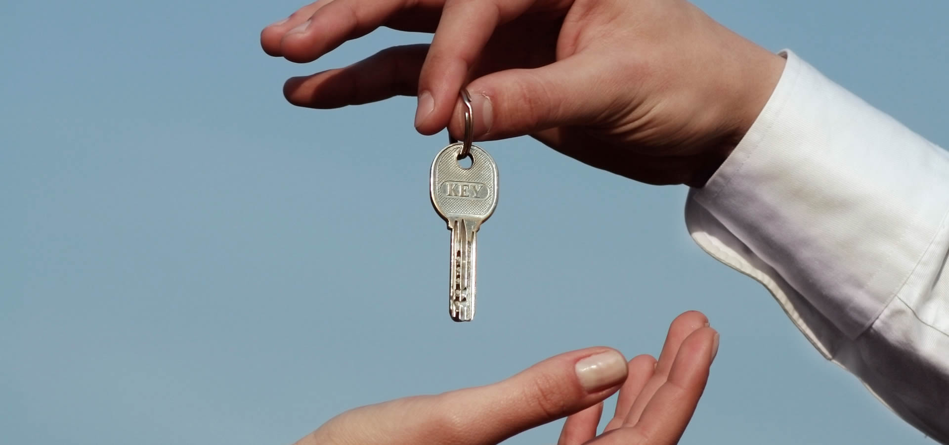 Man's hand passing two keys to woman's hand
